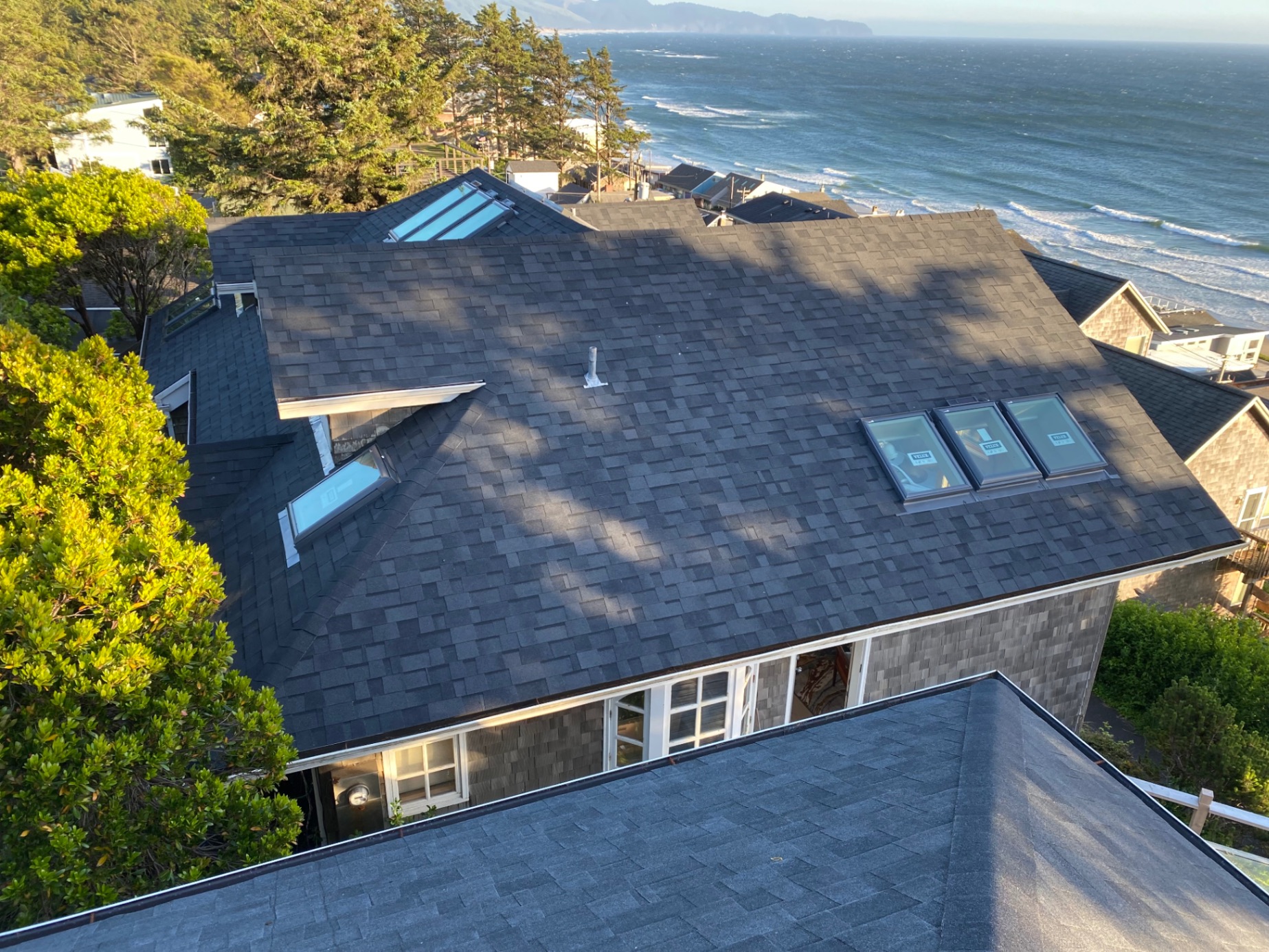 Aerial drone view of completed shingle roof with Oregon coast ocean backdrop — Newport, OR